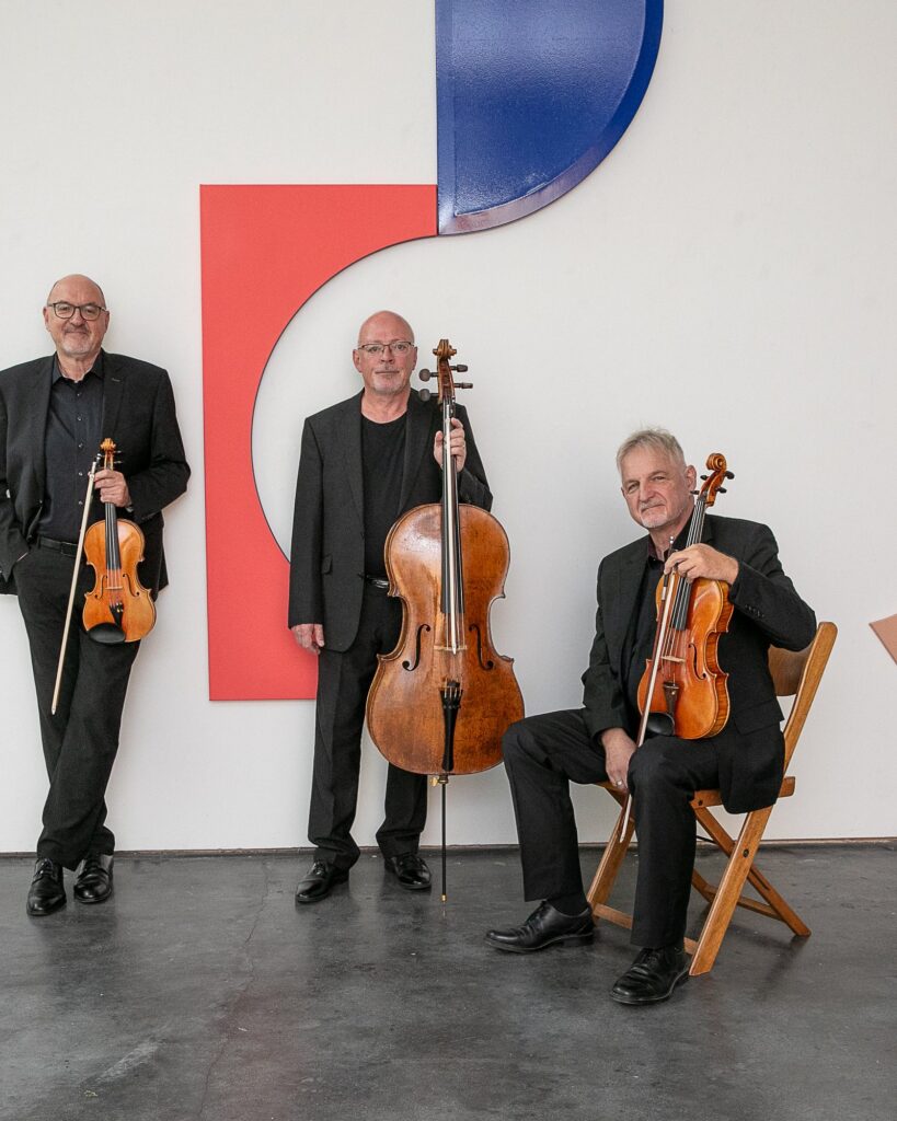 Frank Schilli, Martin Merker und Rolf Schilli vor einer farbigen Wand